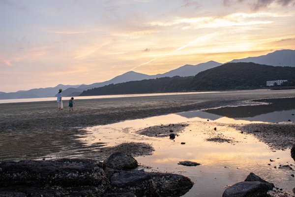 夕暮れの大浜海水浴場を歩く親子