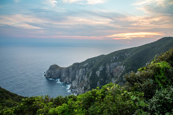 大瀬埼灯台と夕焼け空が広がる断崖の海