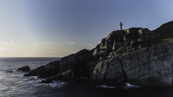 大瀬埼灯台と夕暮れ時の海に臨む断崖