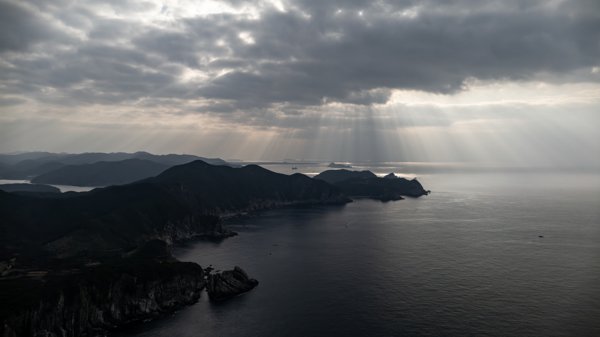 光芒が海に降り注ぐ、雲に覆われた海岸風景